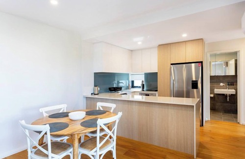 Leederville Apartment | Rooftop Sky Lounge has a daybed, tables and stools, a lounge area with a big screen TV and a grassed