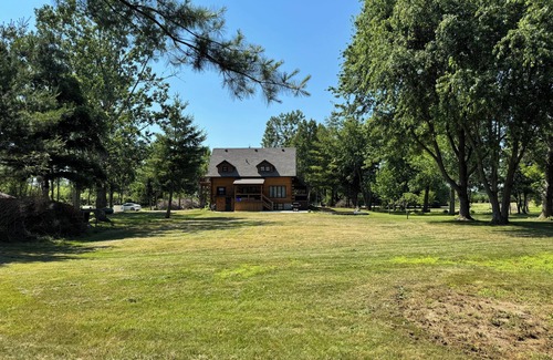 Dunnville House | Serene log home on spacious land with trees and a small farm.