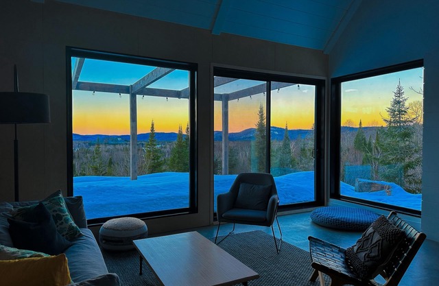 Designer cabin perched above valley, boasts stunning panoramic views.