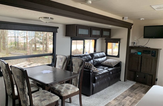 Modern RV camper with all the perks nNestled in tree at lake edge